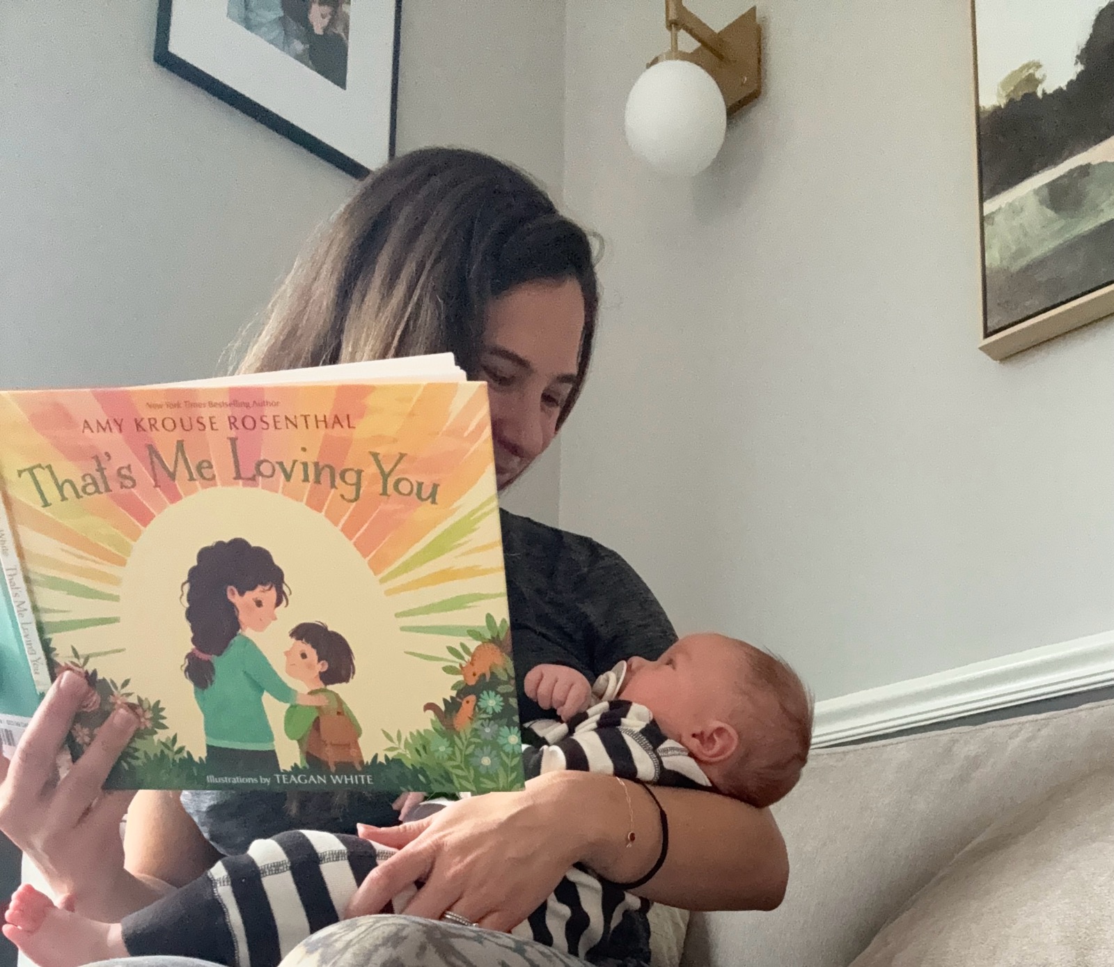 Jenna reading That's Me Loving You while holding her baby